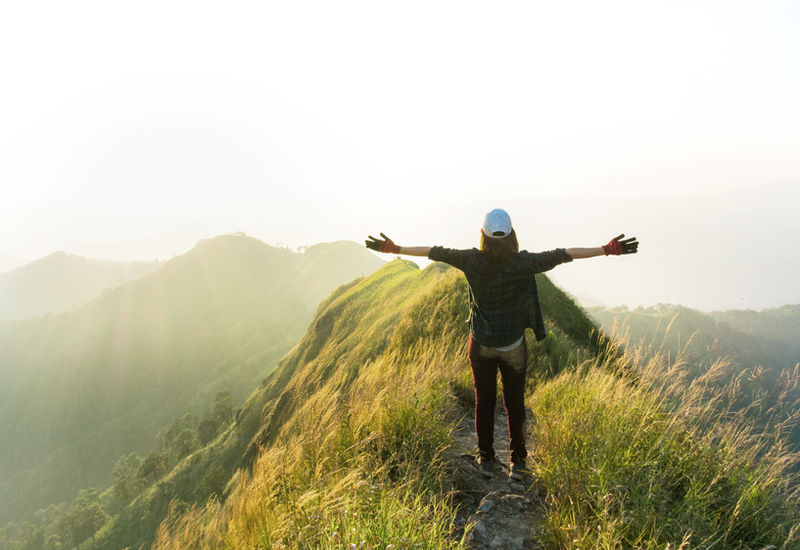 A hiker standing on a mountain with arms open