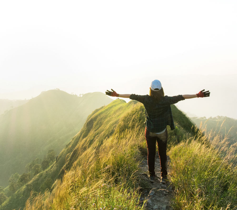 A hiker on a mountain summit with arms outstretched