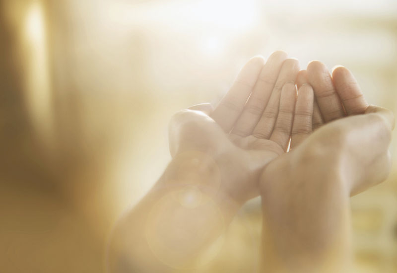 Open hands lifted in prayer in warm light