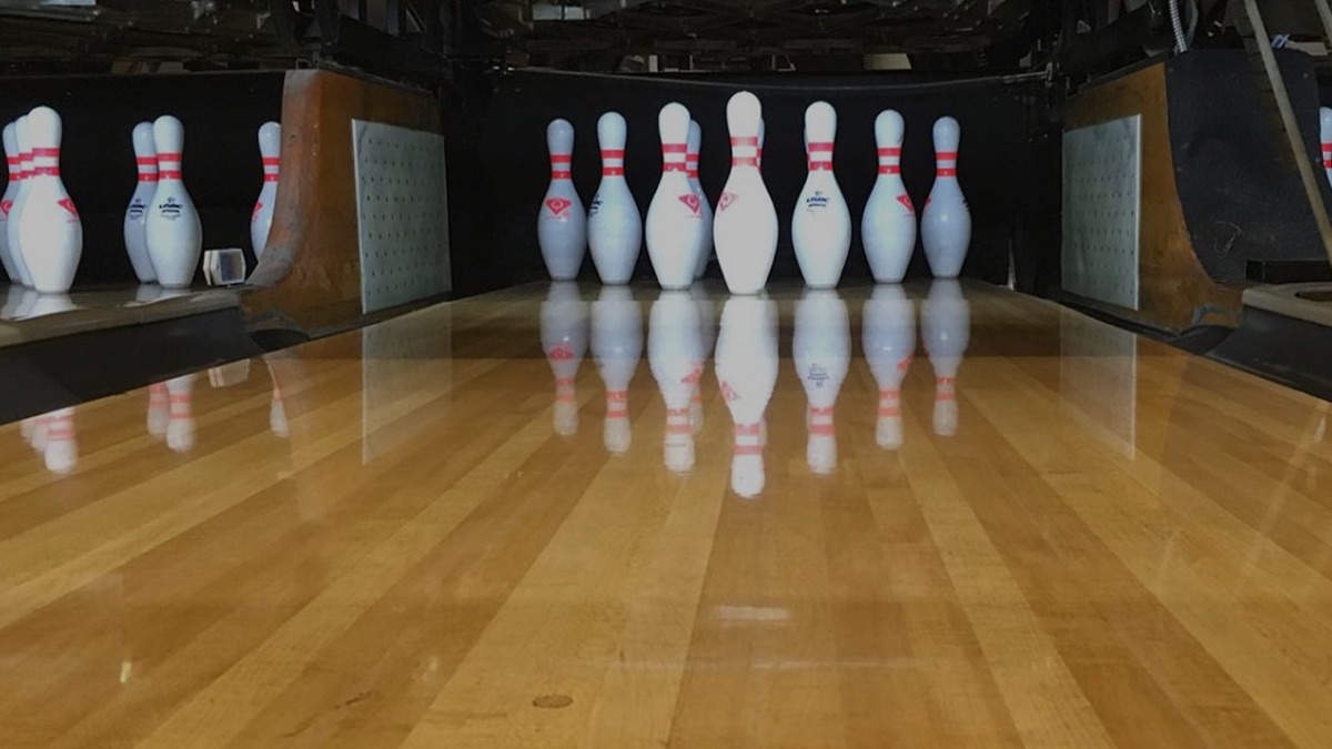 Ten bowling pins racked and waiting at the end of the lane